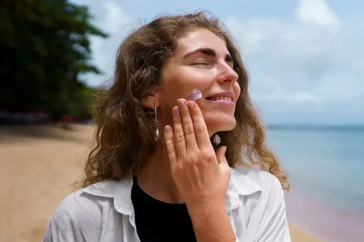 Mulher aplicando protetor solar no rosto ao ar livre